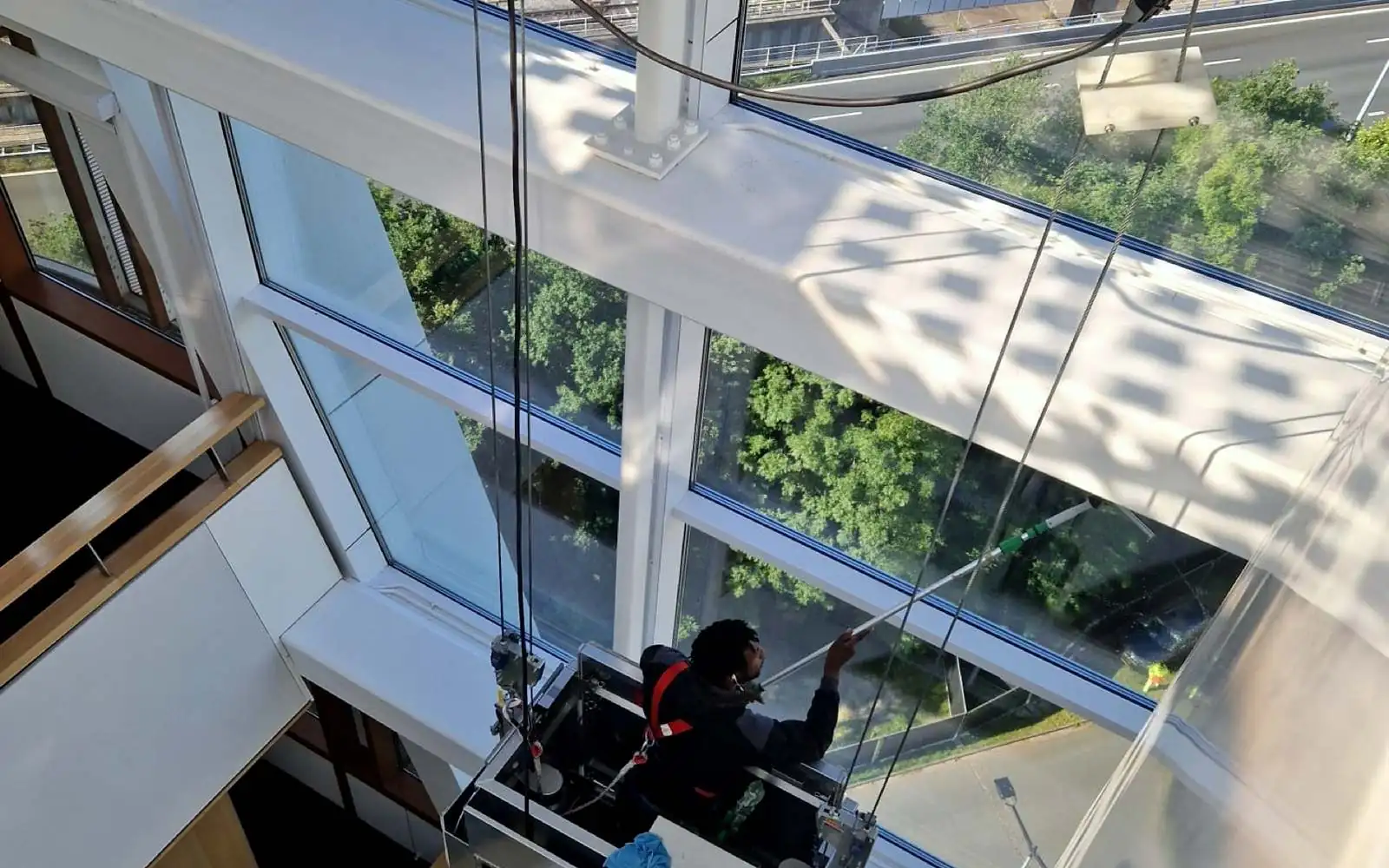Glazenwasser in een gondel wast de ramen van een hoog glazen atrium